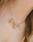 Gold necklace with various charms on a person's neck
