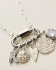 Silver necklace with various charms on a light background