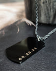 Black dog tag with gold text on a textured surface