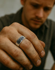 Man wearing a silver ring on his finger with a blurred background