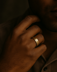 Close-up of a hand wearing a gold ring with a dark background
