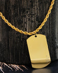 Gold necklace with a dog tag on a textured black surface