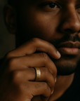 Close-up of a person's hand with a gold ring, against a dark background