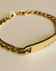 Gold chain bracelet with a nameplate on a light background