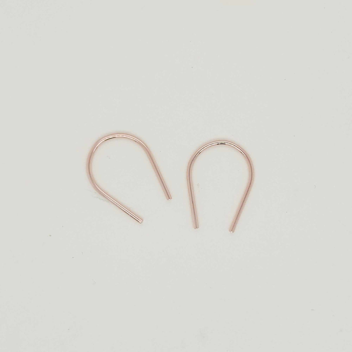 Minimalist gold U-shaped earring pair displayed on white background