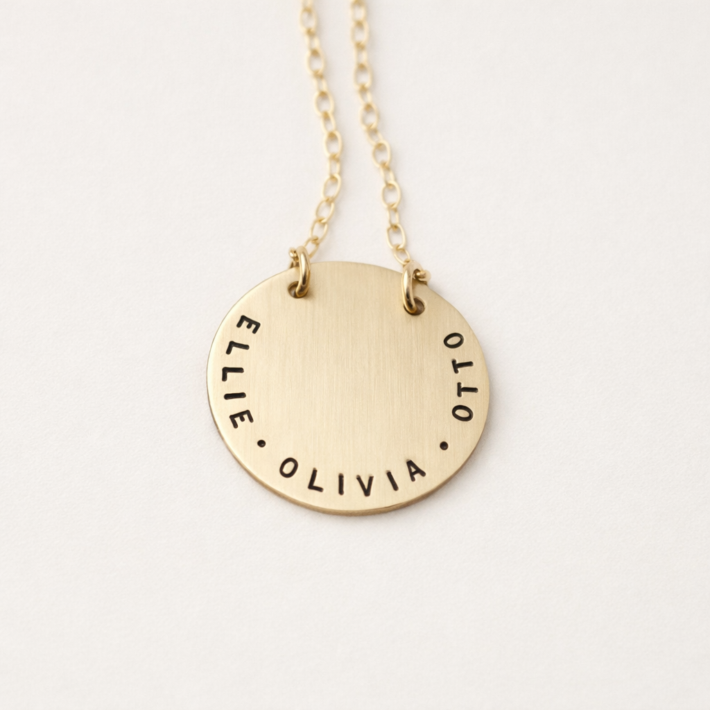 Elegant 1-inch round kids names necklace with personalized stamped names on a brushed sterling silver pendant and classic cable chain