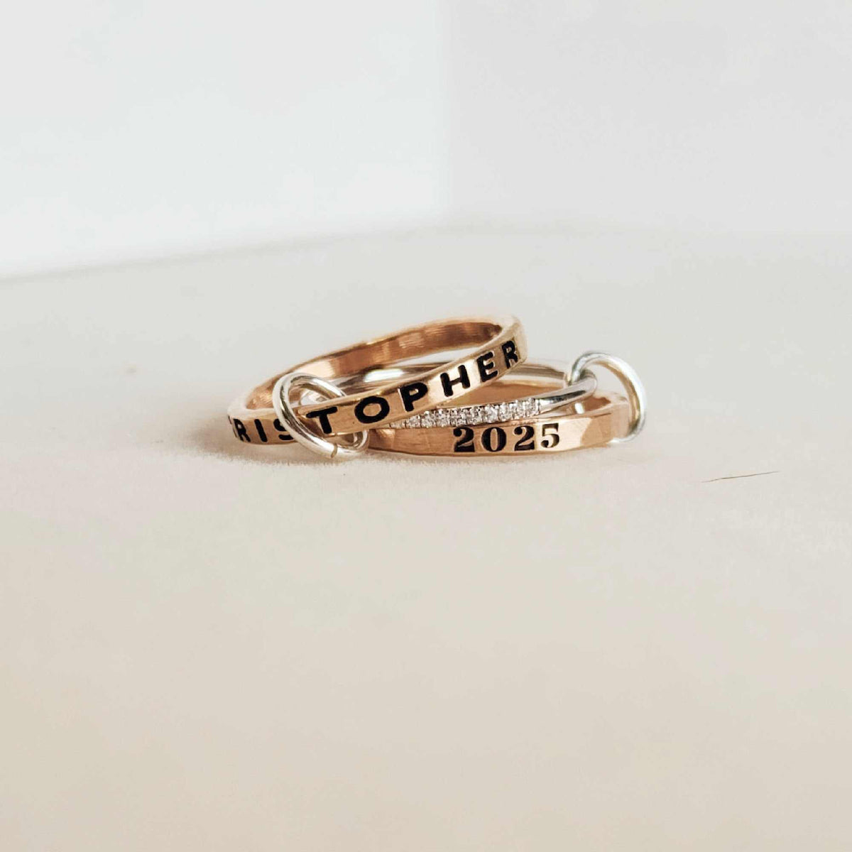 Two rose gold rings with engraved text on a light background