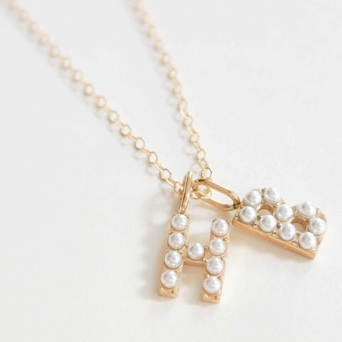 Personalized pearl initial necklace with gold letter charms and faux pearl accents on a delicate gold chain