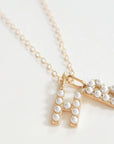 Gold necklace with a letter 'H' and 'B' pendant on a white background