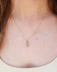 Gold necklace with a letter 'B' pendant worn by a person