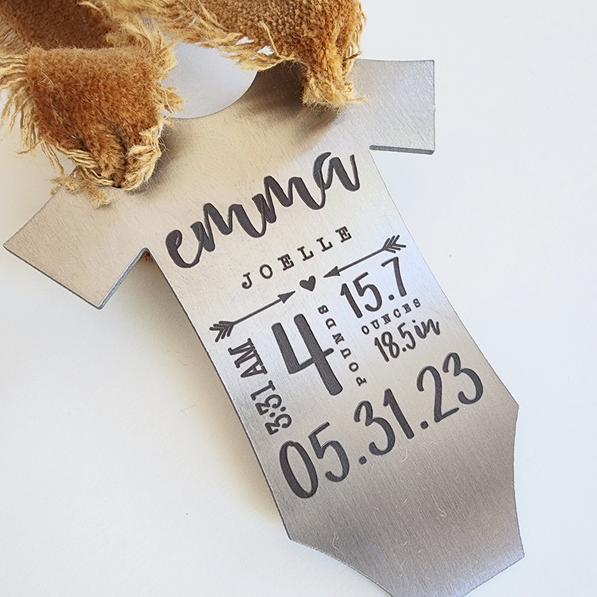 Engraved baby stats ornament with taupe ribbon shown from side angle