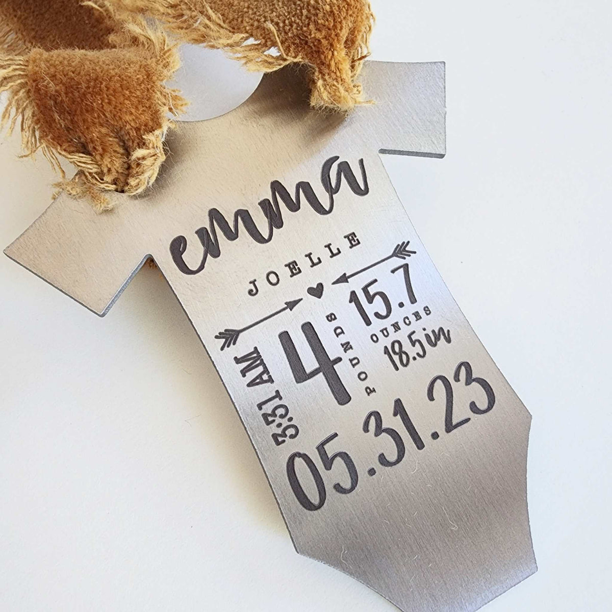 Engraved baby stats ornament with taupe ribbon shown from side angle