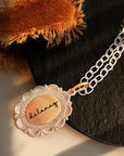 Necklace with a pendant that reads 'balance' on a textured surface.