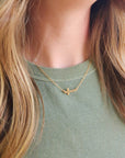 14K gold-filled personalized cross necklace layered with second gold necklace on model wearing green shirt