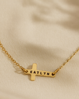 14K gold-filled personalized cross necklace engraved with the name Katlyn on cream background