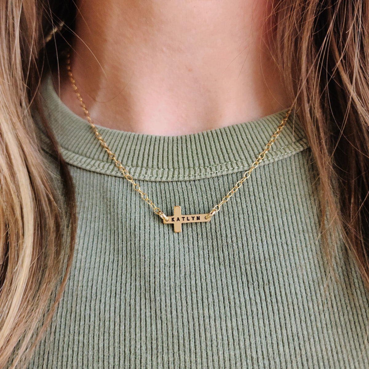 4K gold-filled personalized cross necklace engraved with the name Katlyn on a model’s neck