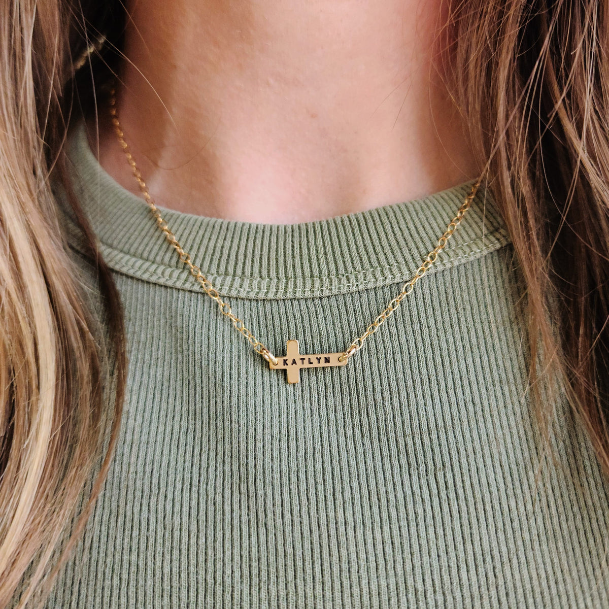 4K gold-filled personalized cross necklace engraved with the name Katlyn on a model’s neck