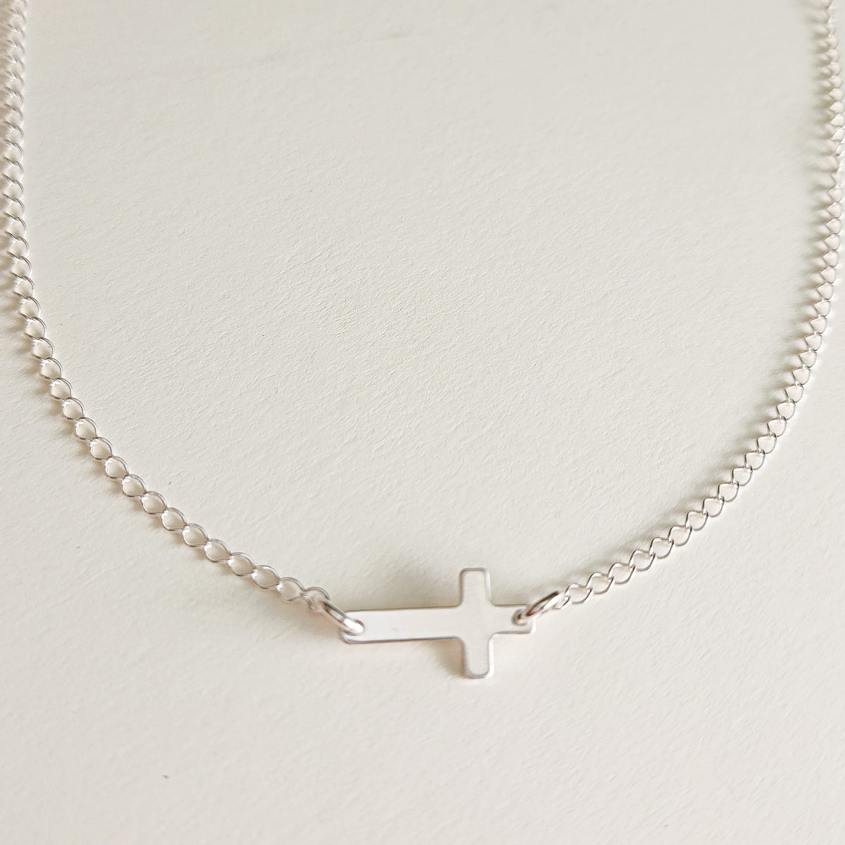 Sterling silver personalized cross necklace with blank engraving space on white background