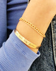A gold-colored cuff bracelet with custom names engraved on it