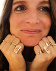 Woman wearing multiple gold rings on her fingers with a blurred background