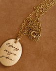 Gold necklace with a round pendant on a brown background