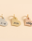 Three heart-shaped gold pendants with engraved text on a beige background
