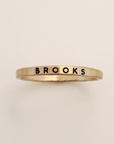 Gold ring with 'BROOKS' engraving on a beige background