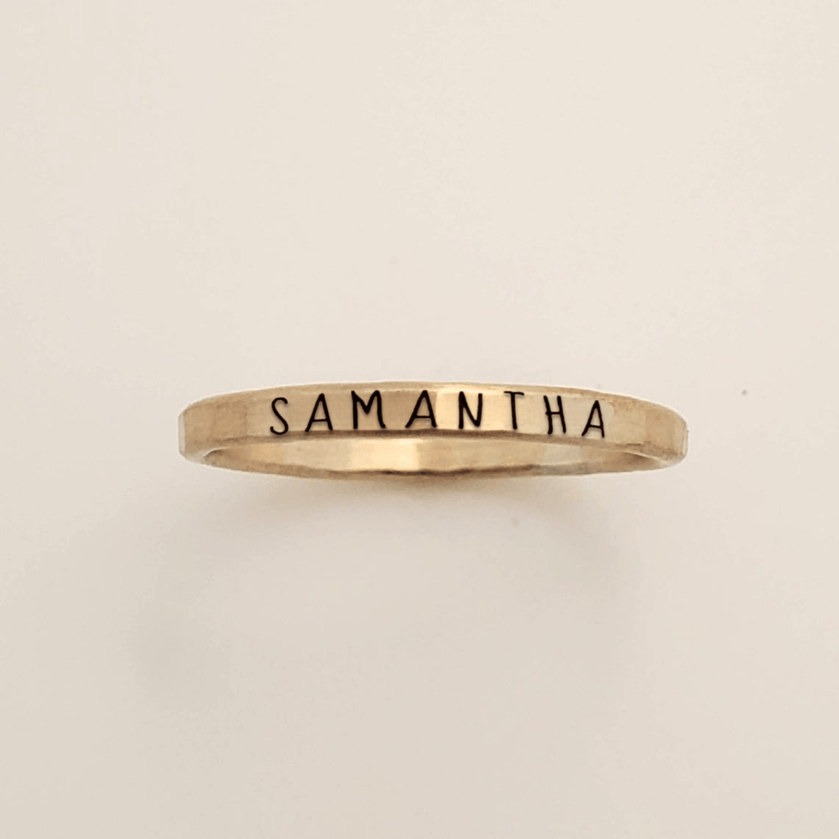 Gold ring with 'Samantha' engraved on a beige background