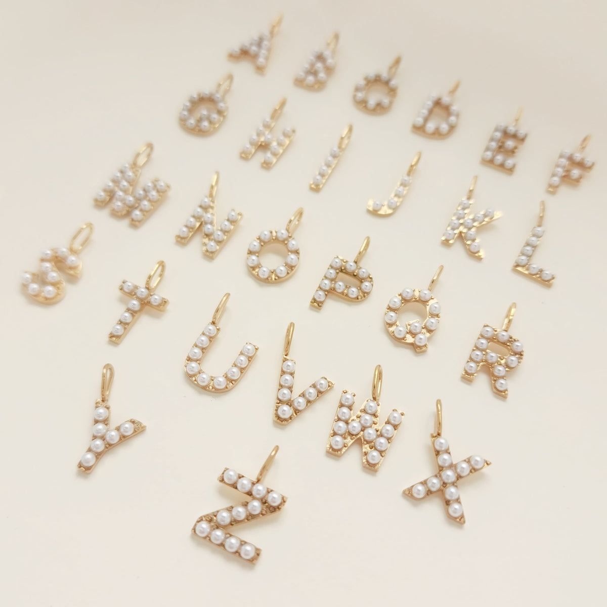 Gold and pearl letter pendants on a beige background