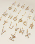 Gold and pearl letter pendants on a beige background