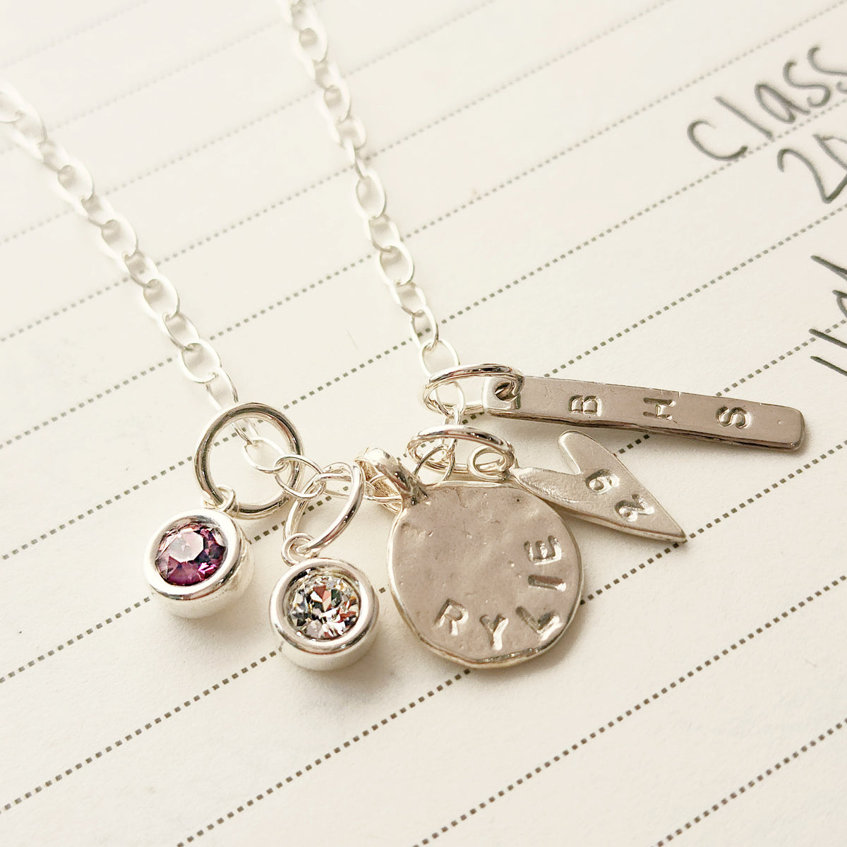 Silver necklace with charms on a lined paper background
