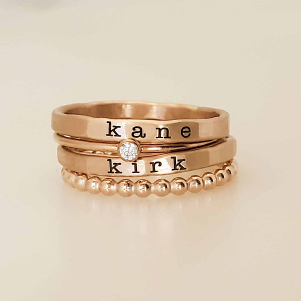 Kennedy Stacking Ring Set with personalized gold name rings, birthstone ring, and beaded spacer ring on hand