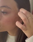 Woman placing gold U-shaped earrings on ear in video demo