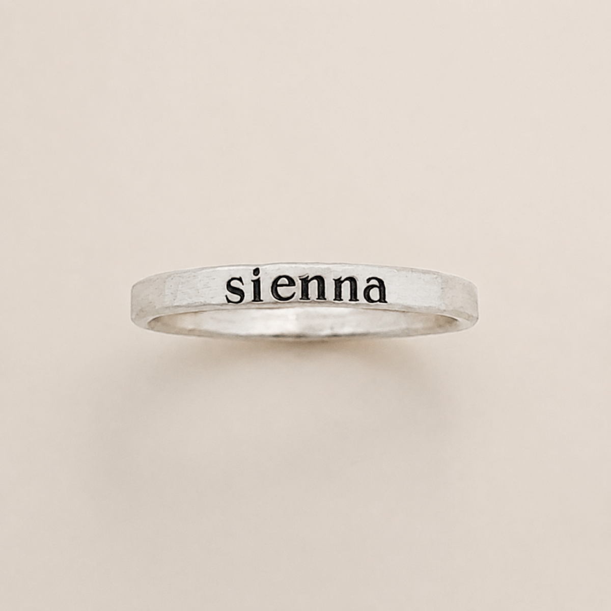 Close-up of personalized stacking ring with serif font engraving in 14k gold filled and rose gold materials