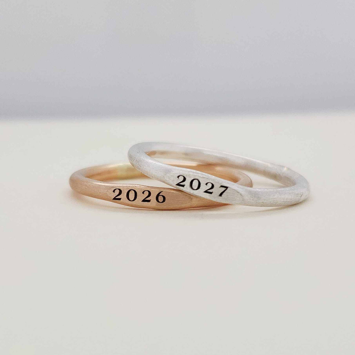 Close-up of Signet Year Stacking Ring with graduation year engraved in polished metal, available in gold and silver options