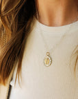 Close-up of a person wearing a gold necklace with a pendant.