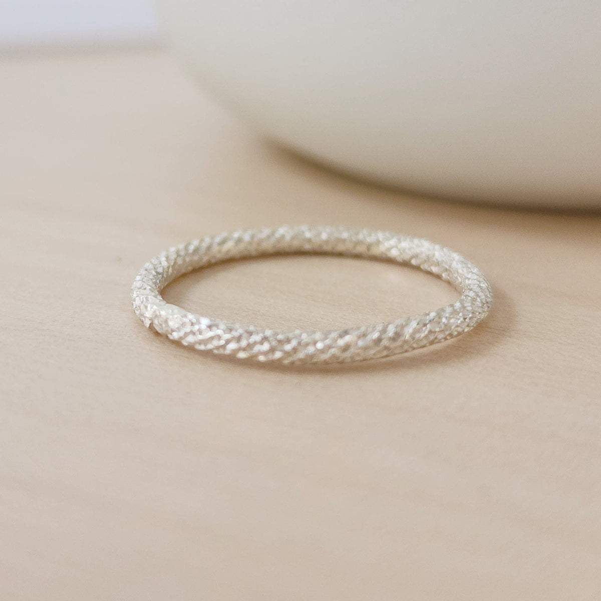 a sterling silver sparkle ring on a tan background