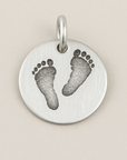 Silver pendant with footprints on a beige background