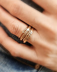 A person's hand showcasing a stack of gold-filled rings, with the focus on the rings' texture and shine.