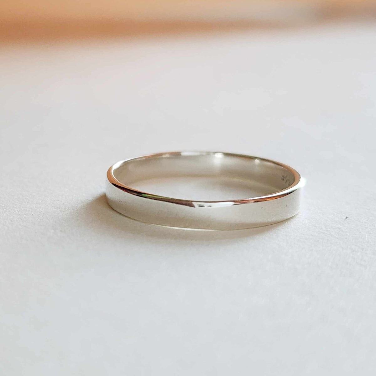 Close-up of smooth polished silver band ring with sleek 2.3mm wide band handcrafted from sterling silver