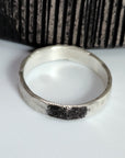 Silver ring with fingerprint design on a white surface