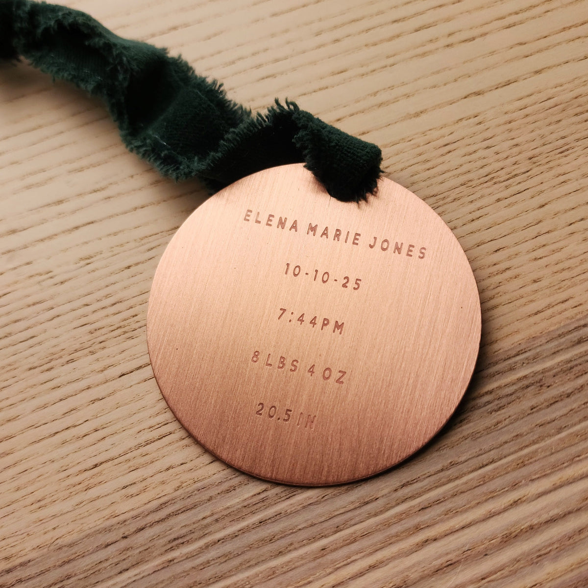 Copper baby birth announcement ornament with engraved details on a wooden surface