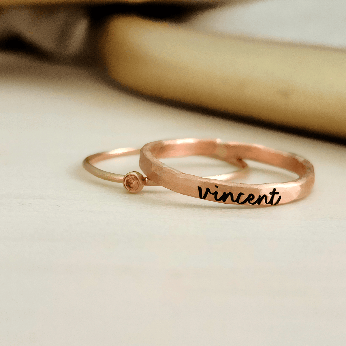 A photo showing a gold-colored ring with the name 'Charlie' engraved on it, worn on a person's finger.