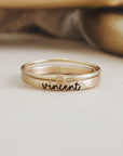 A gold-filled stacking ring set with one ring displaying the name 'Vincent' engraved on it, placed against a neutral background.
