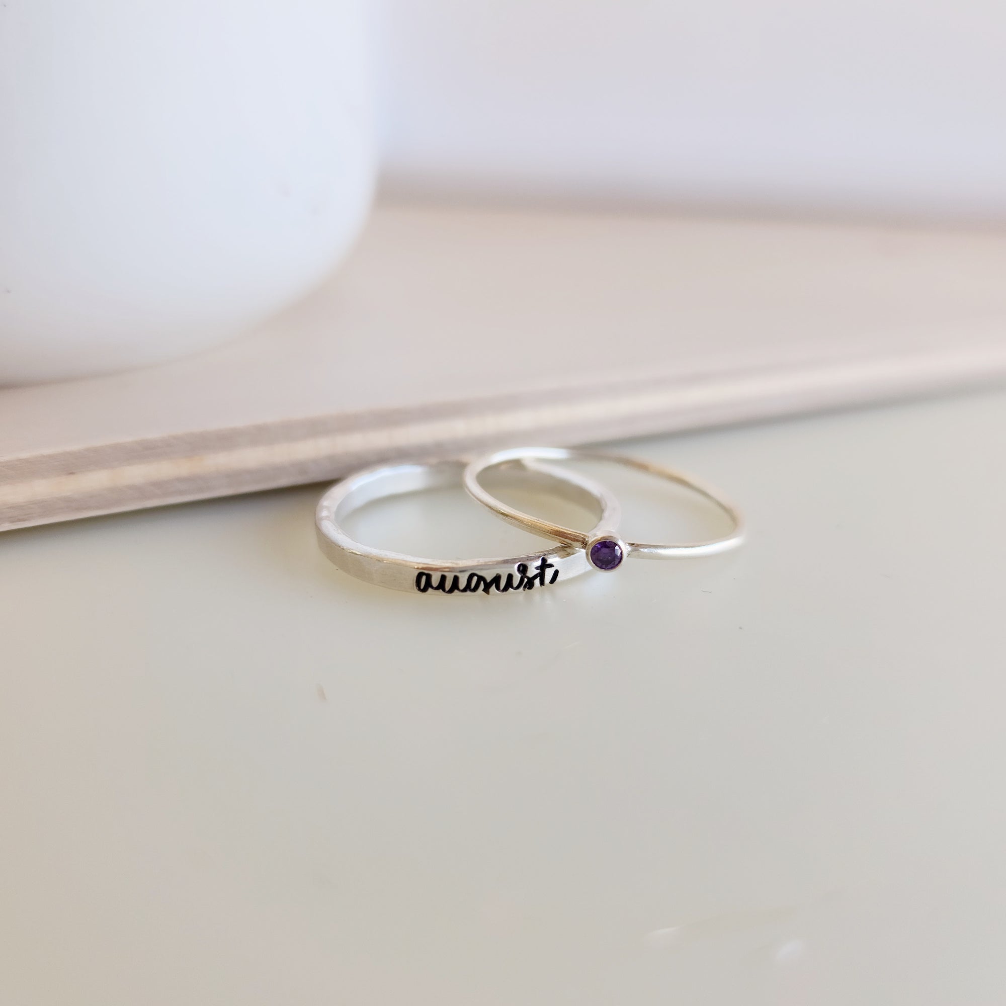 A photo showing a gold-colored ring with the name 'Charlie' engraved on it, worn on a person's finger.