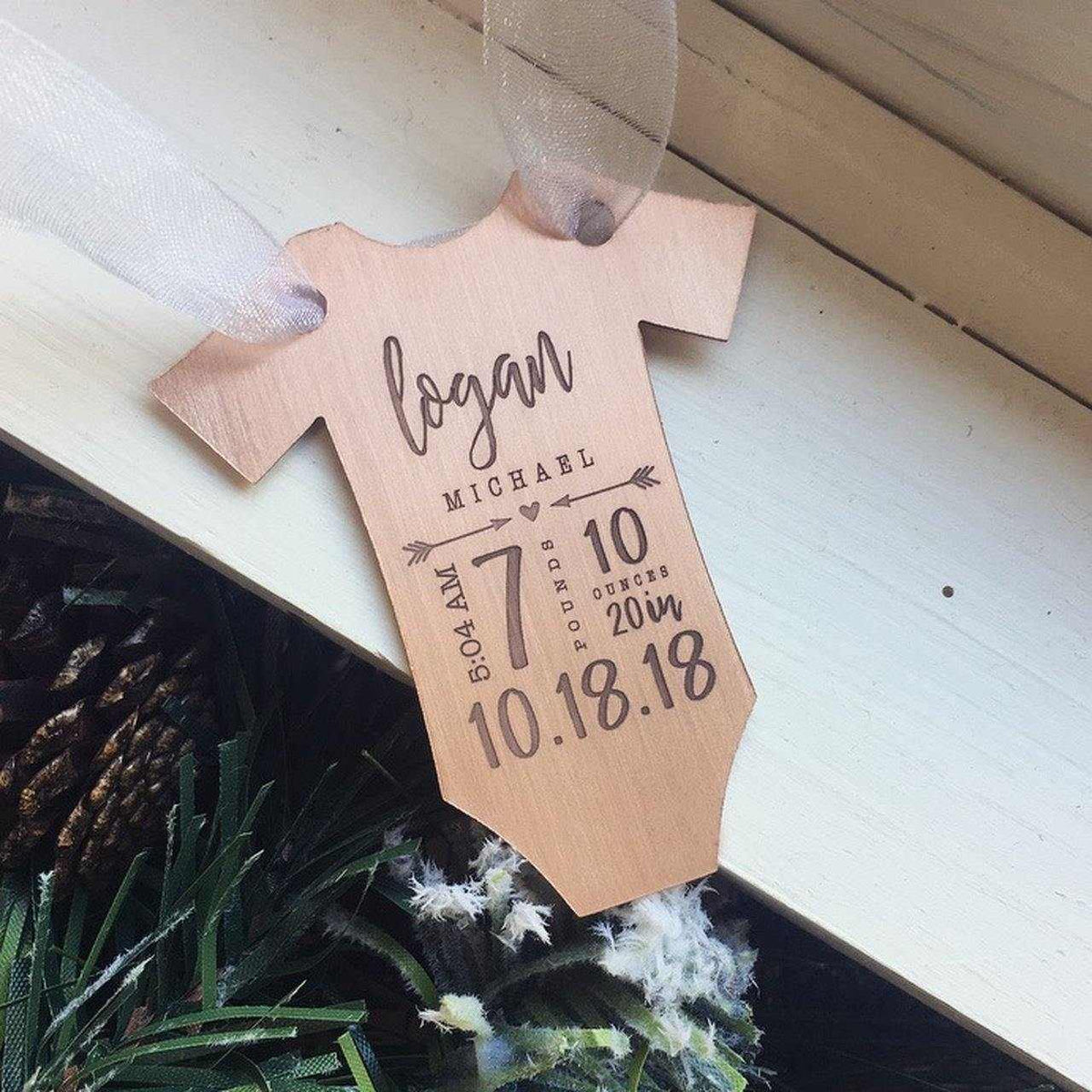Copper baby statistics ornament in onesie shape with birth details engraved, hanging by ribbon.