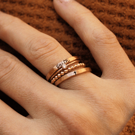 The Faith Stacking Ring Set with gold cross and faith design on a woman's finger