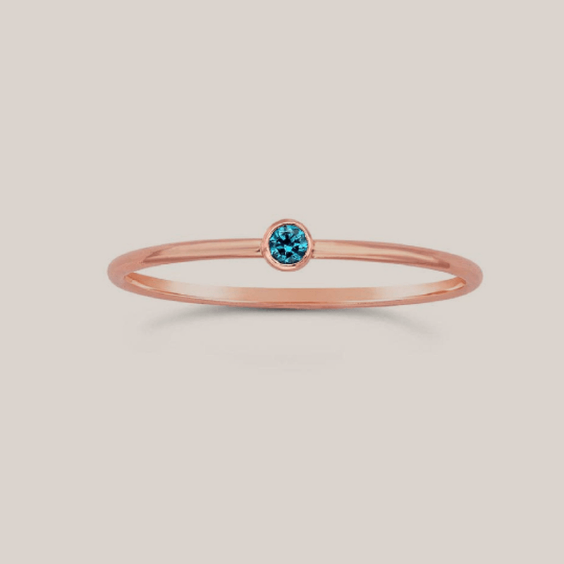 Delicate December birthstone ring with a 2mm blue topaz crystal on a slim 14K rose gold band.