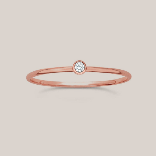 Delicate rose gold April birthstone ring with a single small cubic zirconia on a thin band