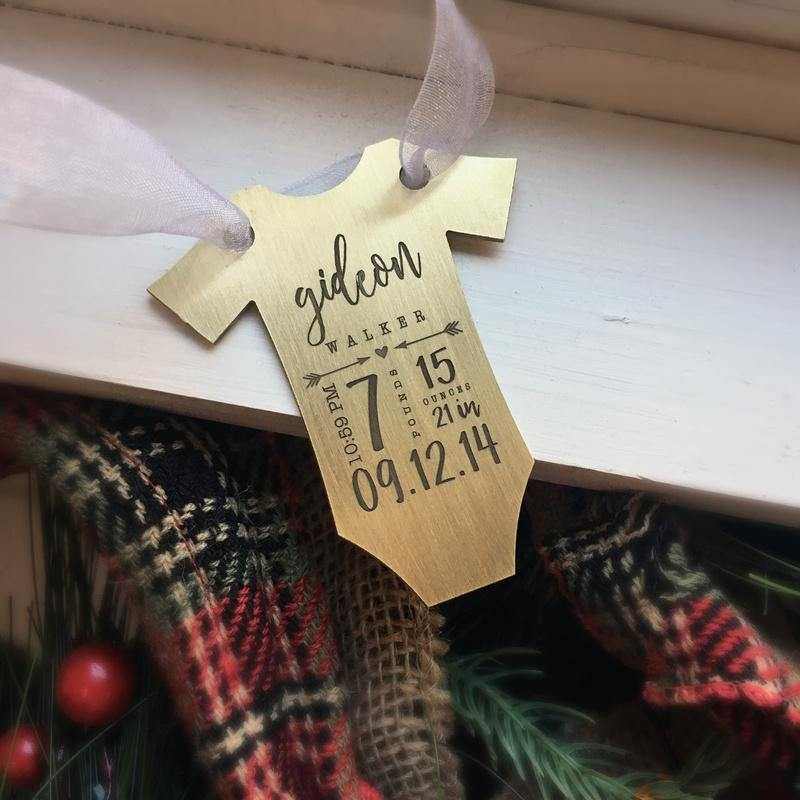 Brass baby bodysuit ornament engraved with birth stats hanging on ribbon